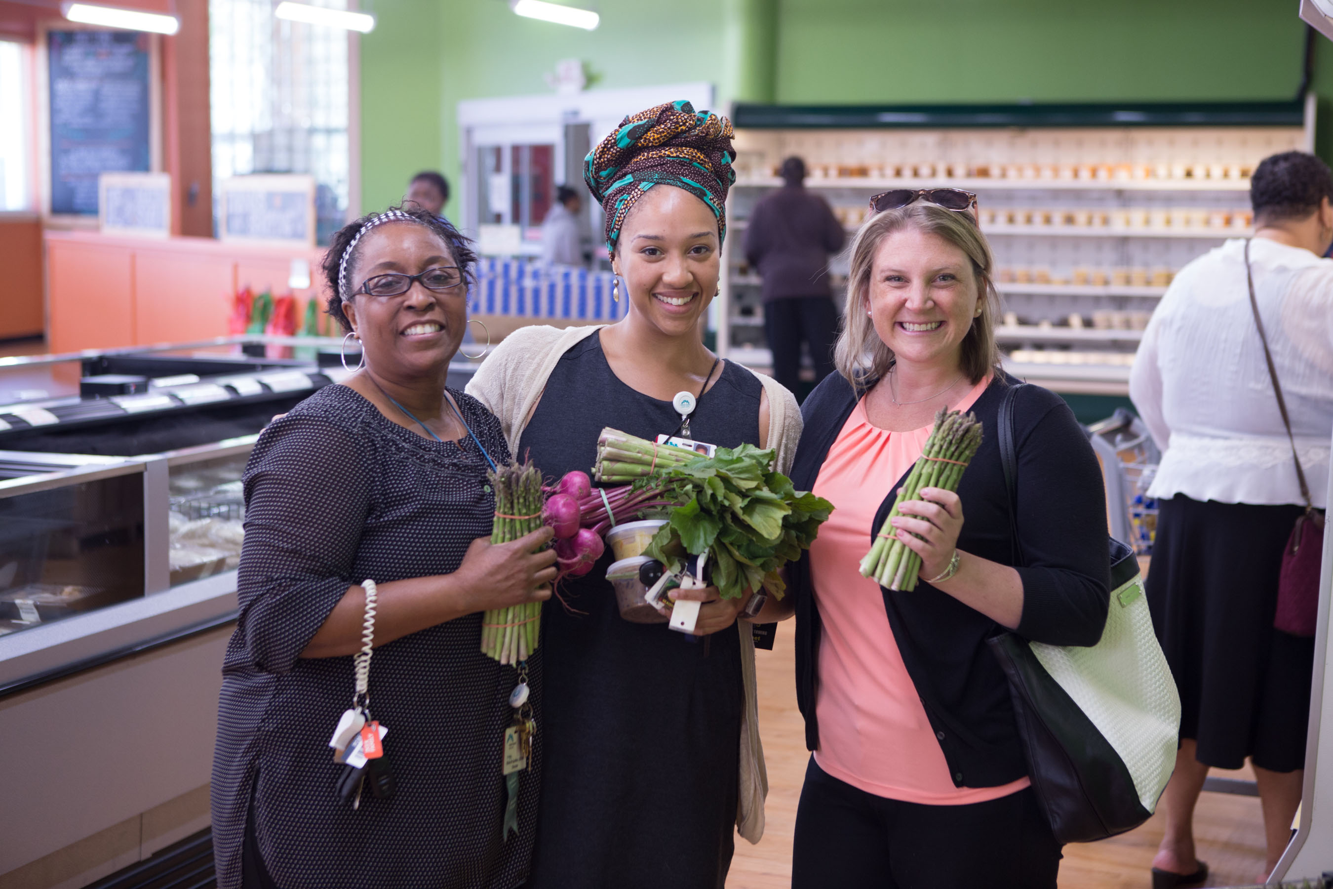 three happy Daily Table customers holding up veggies