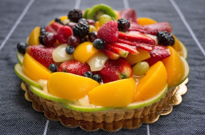 A fresh homemade fruit tart on a tablecloth from pastiche